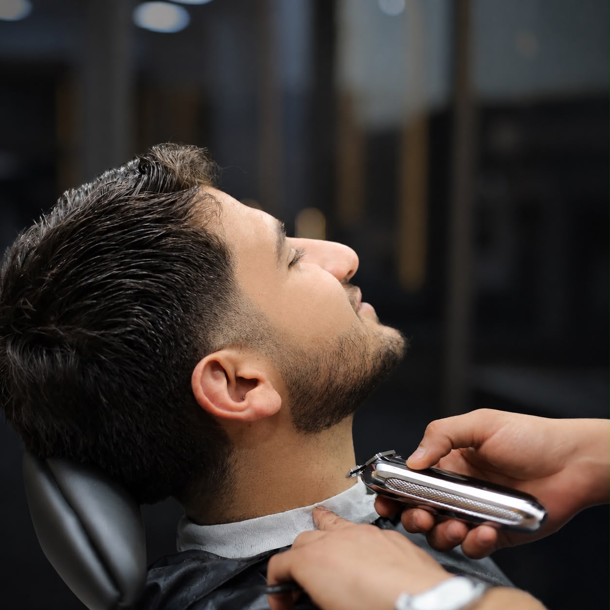Barber trimming a client's beard and neckline with clippers